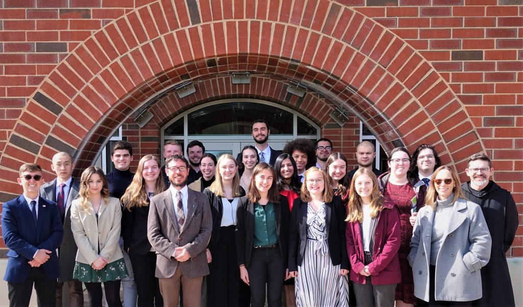 The students and faculty of the 2022 Student Conference at St. Vincent College standing in front of a brick archway.